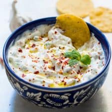 A close up of A picture of Garlicky yogurt party dip served in a blue bowl with chips