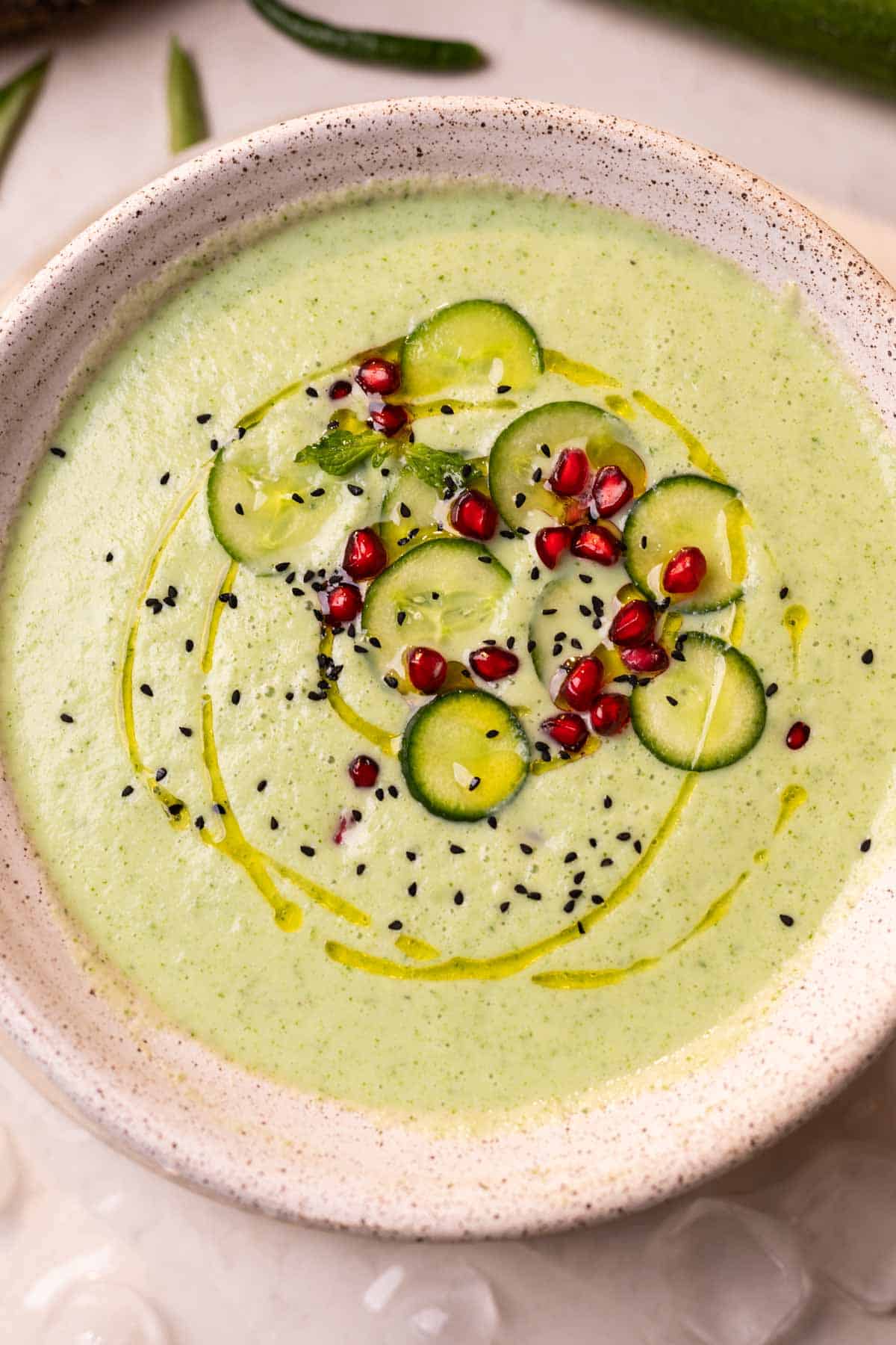 cold cucumber soup garnished with cucumber slices, pomegranate and nigella seeds ready to be served