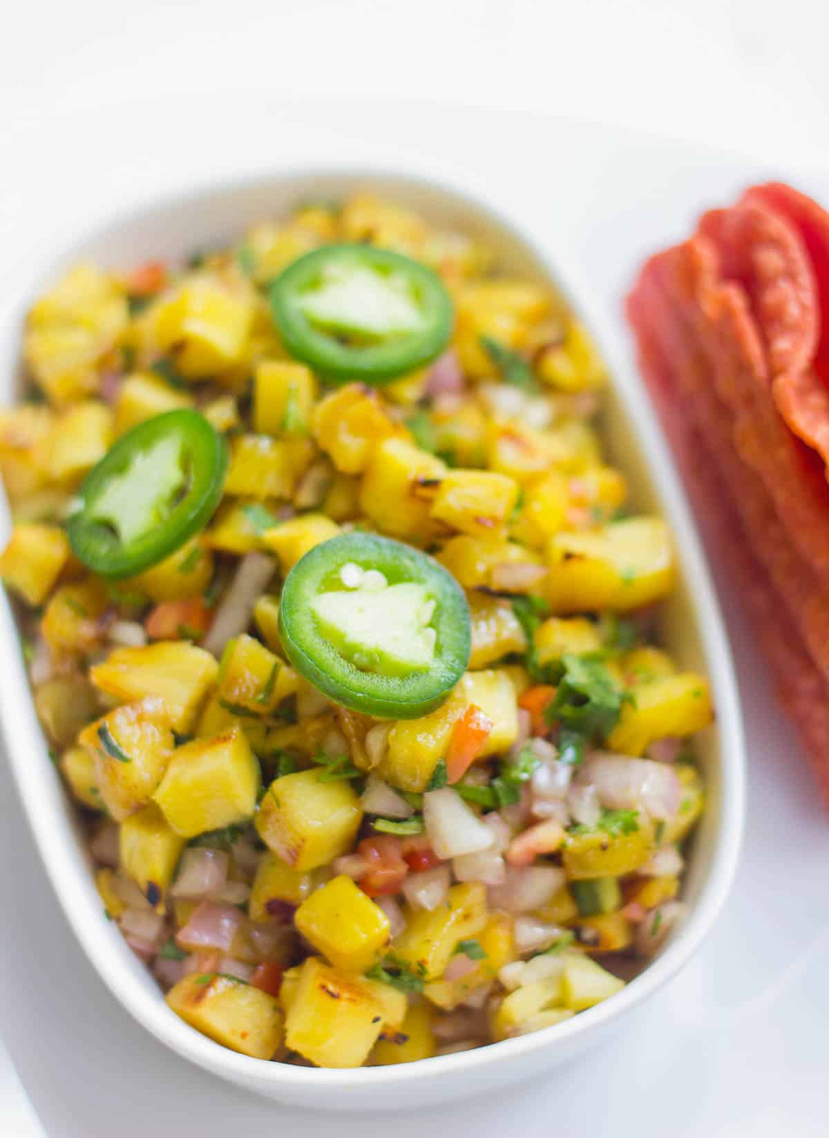 Spicy Grilled Pineapple Salsa garnished with Jalapeño and served in a white dish.