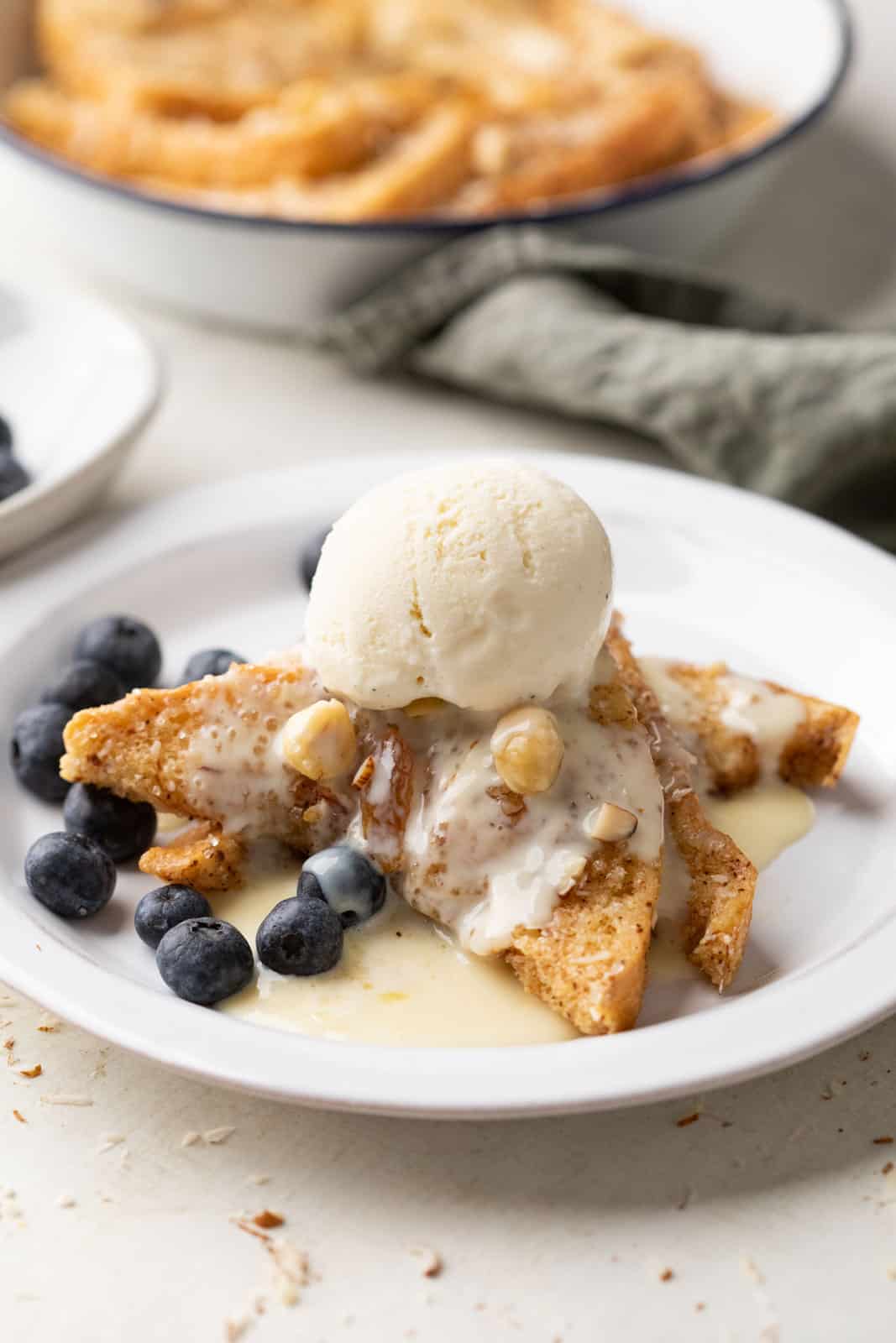 Cinnamon bread pudding served on a plate topped with rum custard sauce and a scoop of ice cream