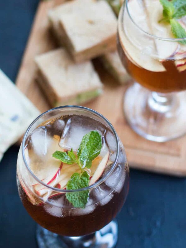 Two glasses of Virgin Apple Iced Tea with sandwiches placed on a cream colour tray