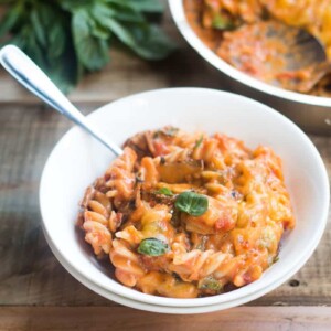 A comforting bowl of cheesy Sunday Veggie Pasta garnished with fresh basil and served in a white bowl.