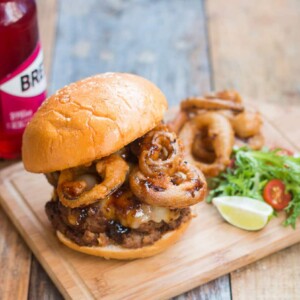The wholesome badass burger plated with salad, onion rings and a Breezer on the side.