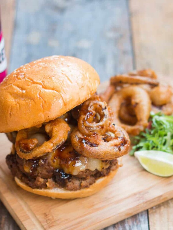 The wholesome badass burger plated with salad, onion rings and a Breezer on the side.