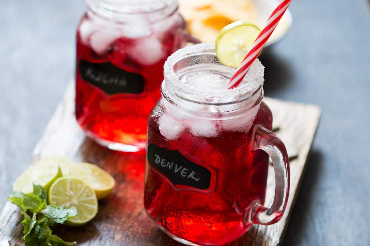 Cranberry Ginger Holiday Cocktail served in mason jars with sugar coated rims and a slice of lime.
