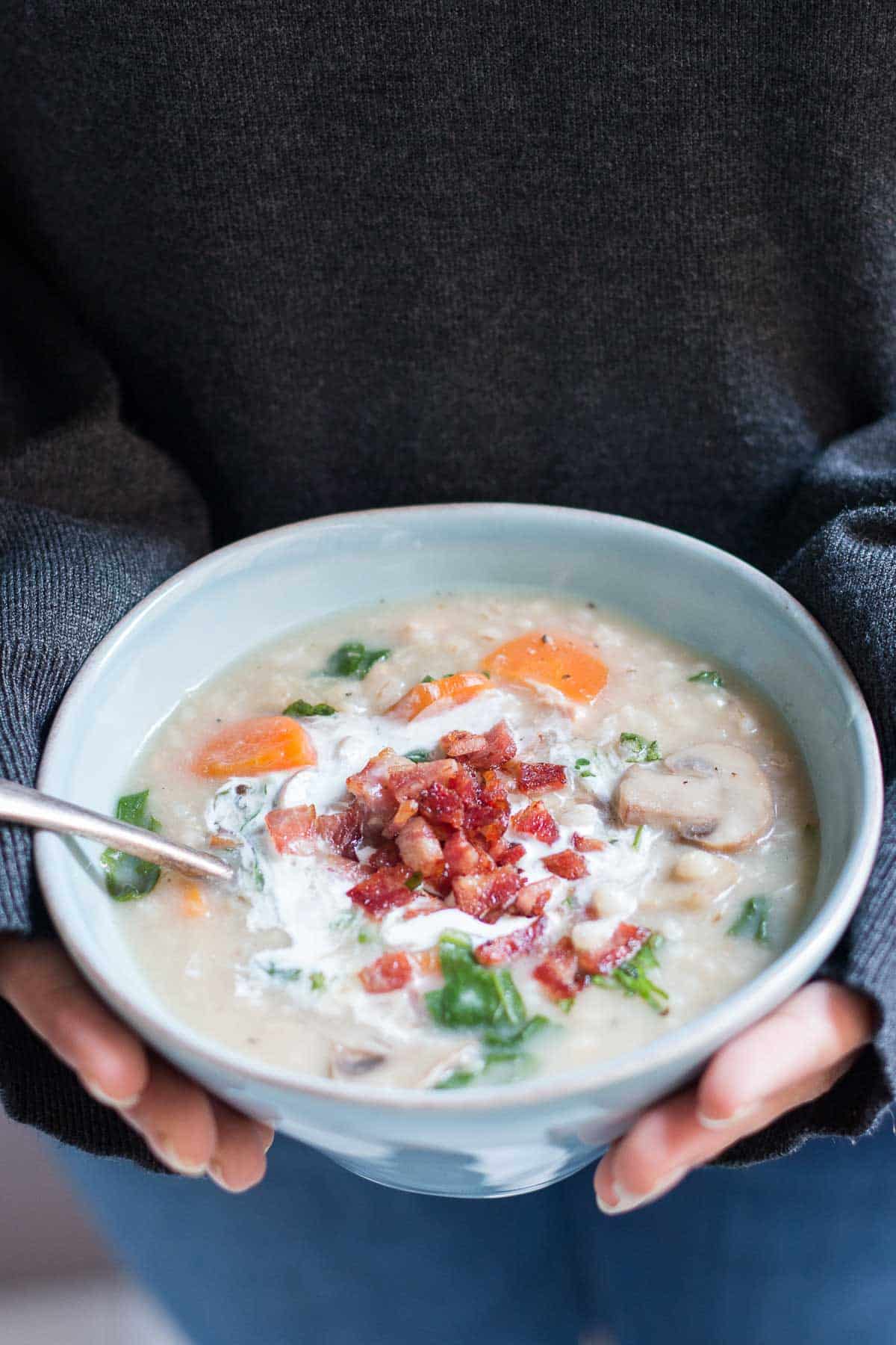 The soup garnished with bacon and cream and served in a white bowl.
