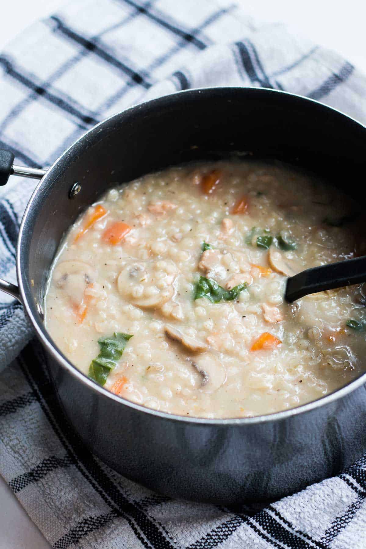The barley chicken soup in a black pot, ready to be served.