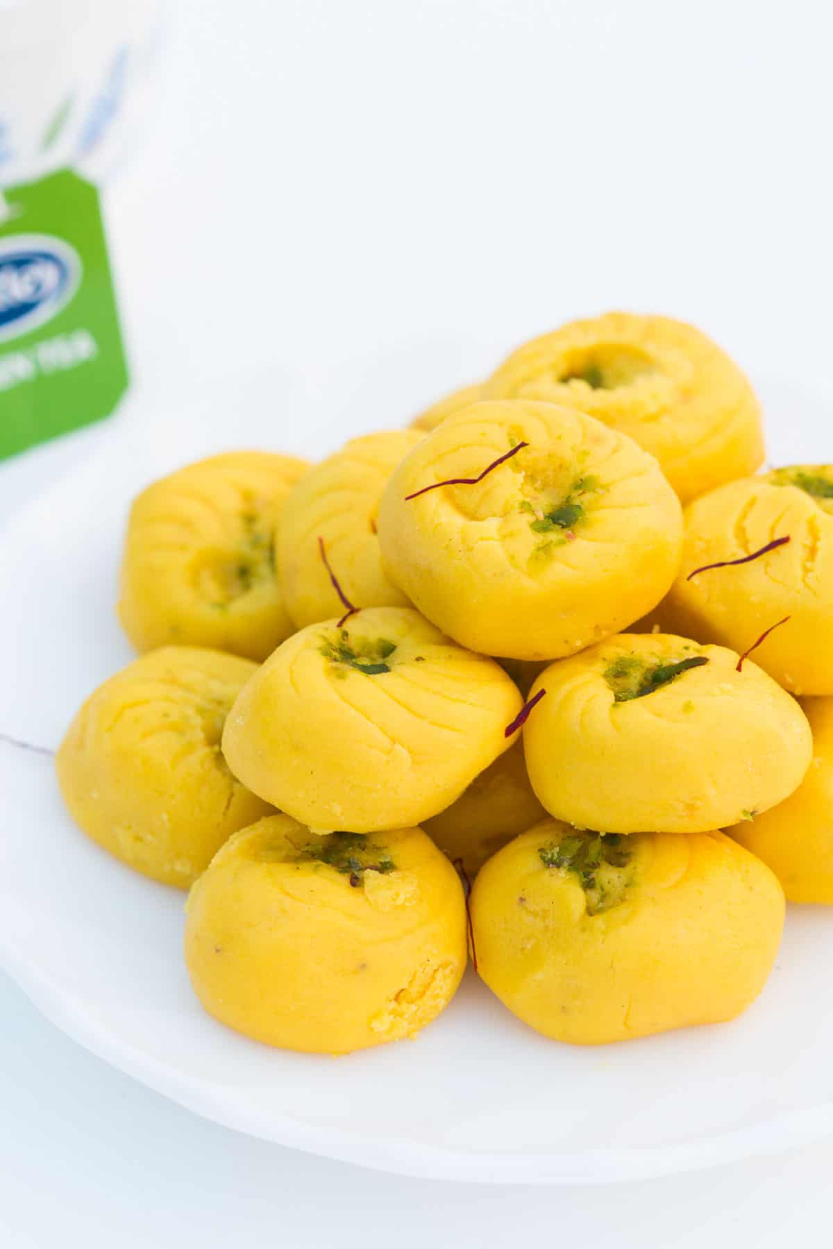 Easy Kesar Pedas served on a white plate with a side of Tetley green tea.