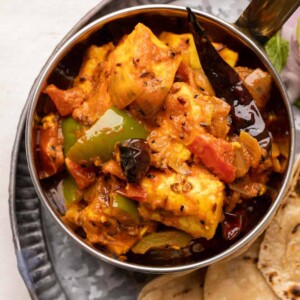 Achari Paneer served in a copper steel bowl with rotis on the side