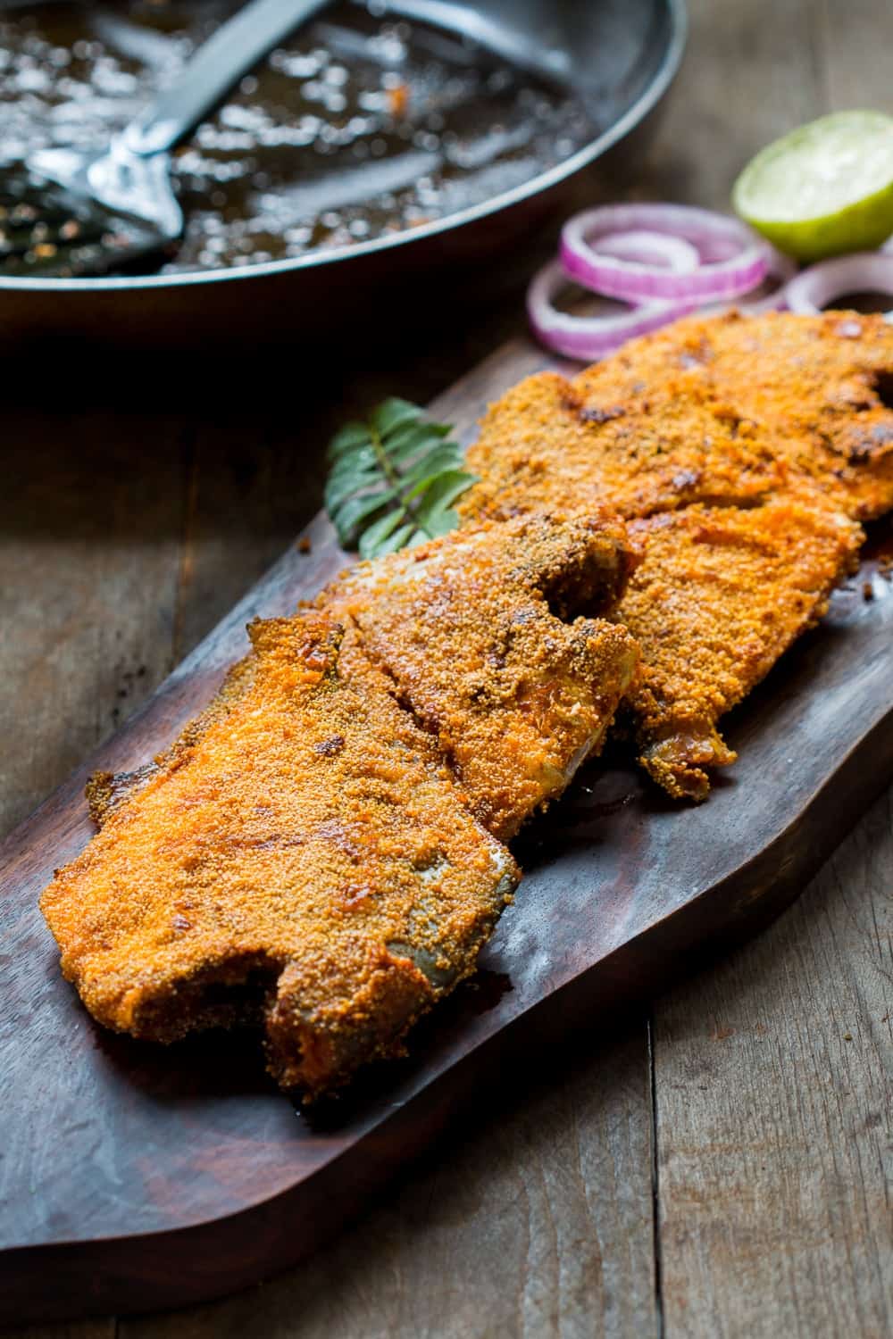 the fried fish coated with rava aka semolina served on a wooden board