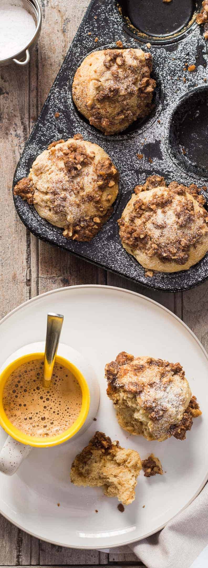 cinnamon roll muffins with crunchy streusel top in a baking tin with with a beverage and muffins in a plate