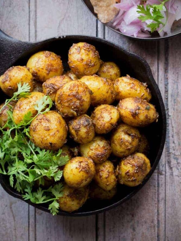 Bombay potatoes garnished with coriander and served in a black pan.
