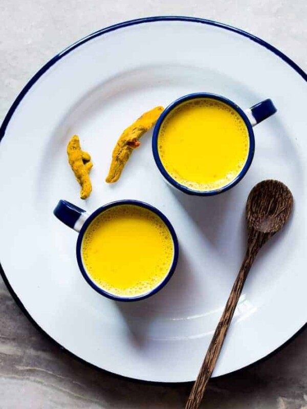 Haldi doodh served in cups kept on a white plate.