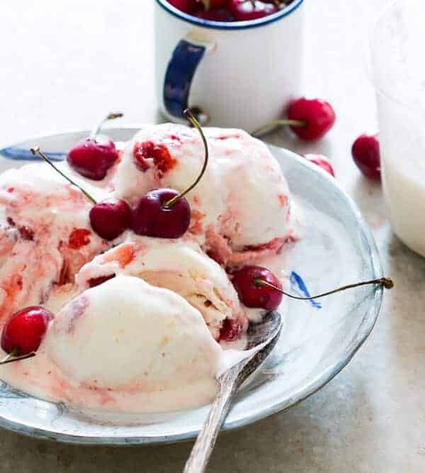 Lychee Cherry Swirl Ice Cream garnished with cherries and served on a white plate.