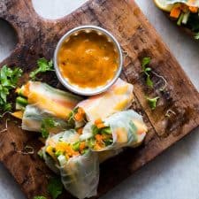 Mango Bell Pepper Rice Paper Rolls with Mango Cilantro Dipping Sauce served on a wooden board.