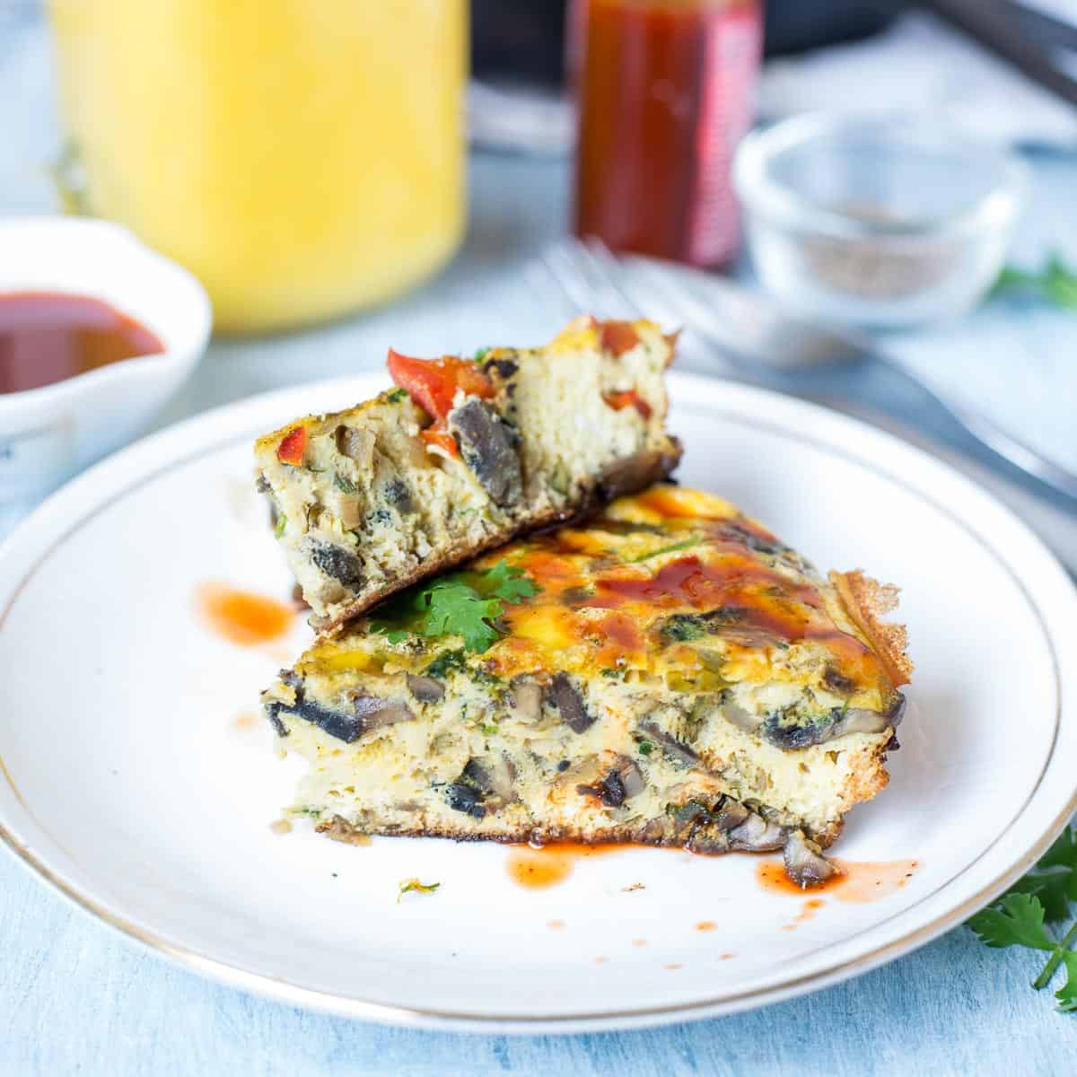 One Pan Indian Masala Omelette Frittata drizzled with sriracha and served on a white plate.
