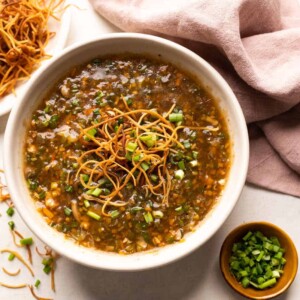 Chicken Manchow soup served in a white bowl topped with fried noodles and spring onions