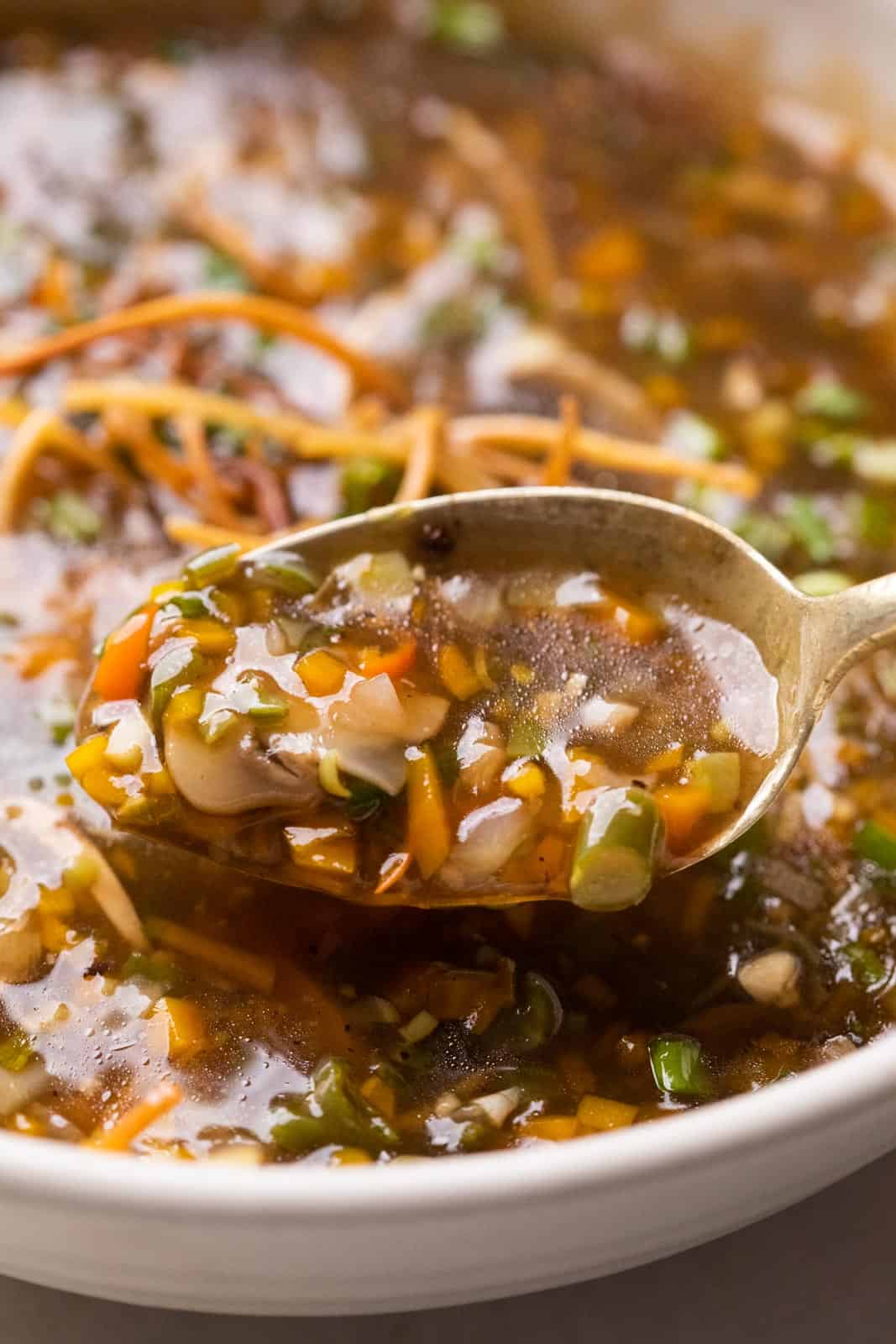 Chicken Manchow soup served in a white bowl topped with fried noodles and spring onions