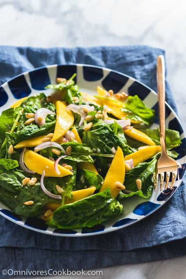 A collection of 13 insanely delicious savoury mango recipes that are sure to blow your mind if you've always had mangoes in sweet dishes. These recipes combine the juicy sweetness of mangoes with savoury ingredients to create a dish that's truly stellar and unforgettable! #spring #mango #recipes #easter #summer #fruit Spinach mango salad in a black and white bowl with a fork