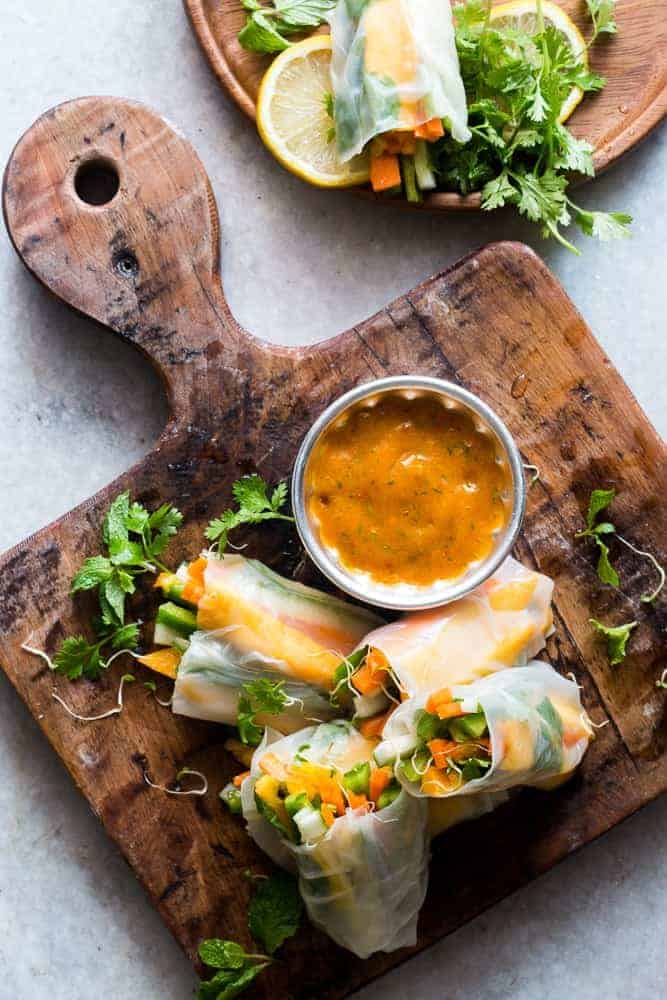A collection of 13 insanely delicious savoury mango recipes that are sure to blow your mind if you've always had mangoes in sweet dishes. These recipes combine the juicy sweetness of mangoes with savoury ingredients to create a dish that's truly stellar and unforgettable! #mango #recipes #summer #spring #appetizers #easter Picture of mango bell pepper spring rolls on a wooden board for the savoury mango recipes roundup
