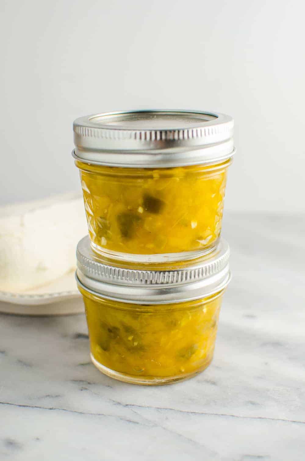 A collection of 13 insanely delicious savoury mango recipes that are sure to blow your mind if you've always had mangoes in sweet dishes. These recipes combine the juicy sweetness of mangoes with savoury ingredients to create a dish that's truly stellar and unforgettable! #spring #mango #recipes #easter #summer #fruit Mango jalapeno jam stored in two glass jars with lid, stacked on top of the other