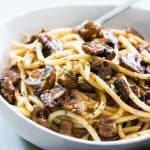 Mushroom spaghetti garnished with parmesan cheese and served in a white bowl.