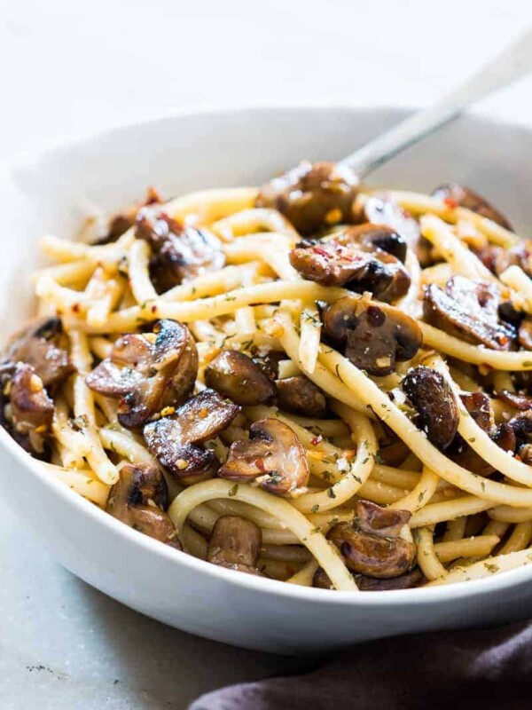 Mushroom spaghetti garnished with parmesan cheese and served in a white bowl.