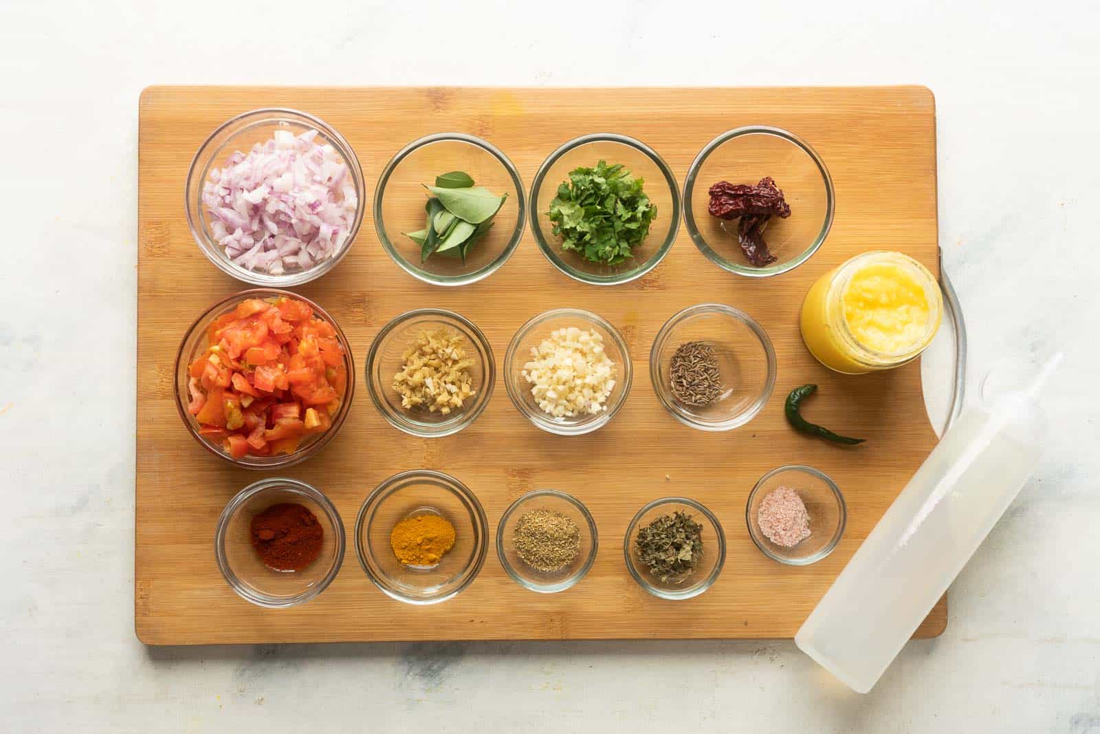 Ingredients required for dal tadka laid out on a wooden chopping board