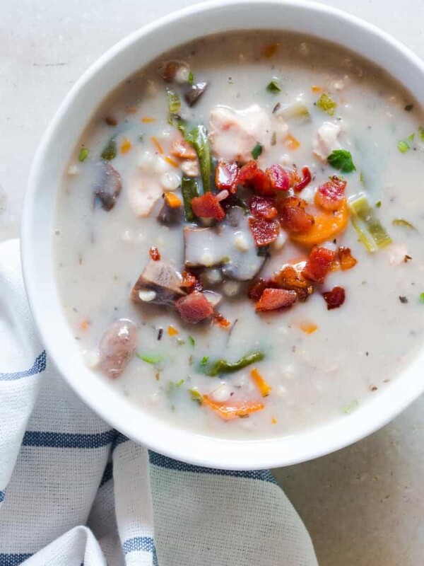 Creamy Slow Cooker Chicken Barley Soup topped with fried bacon and served in a white bowl.