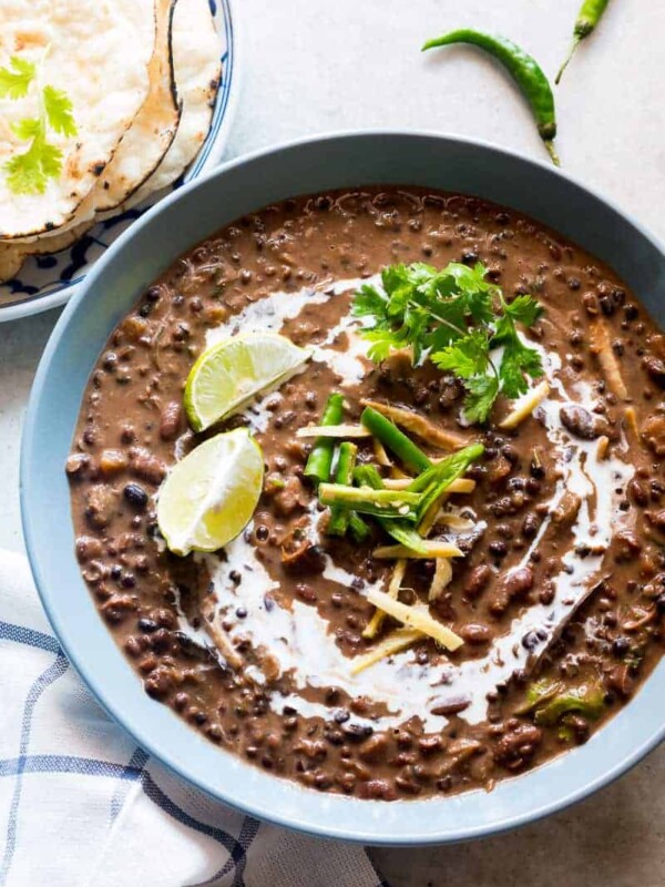 Dal Makhani topped with cream, coriander, ginger, lime and served in a blue bowl.