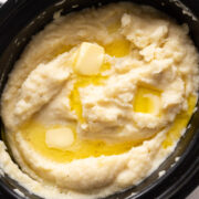 Mashed potatoes cooked and served in the slow cooker with blobs of butter on top