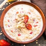 Healthy Strawberries and Cream Breakfast Oatmeal drizzled with honey, chia seeds and served in a wooden bowl.