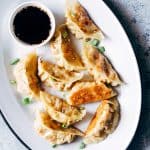 Vegetarian Gyoza Potstickers with Carrot and Paneer served with a dipping sauce on a white plate.