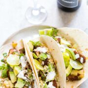 Tilapia Fish Tacos with Pineapple Salsa served on a white plate with a side of Big Banyan's sauvignon blanc.