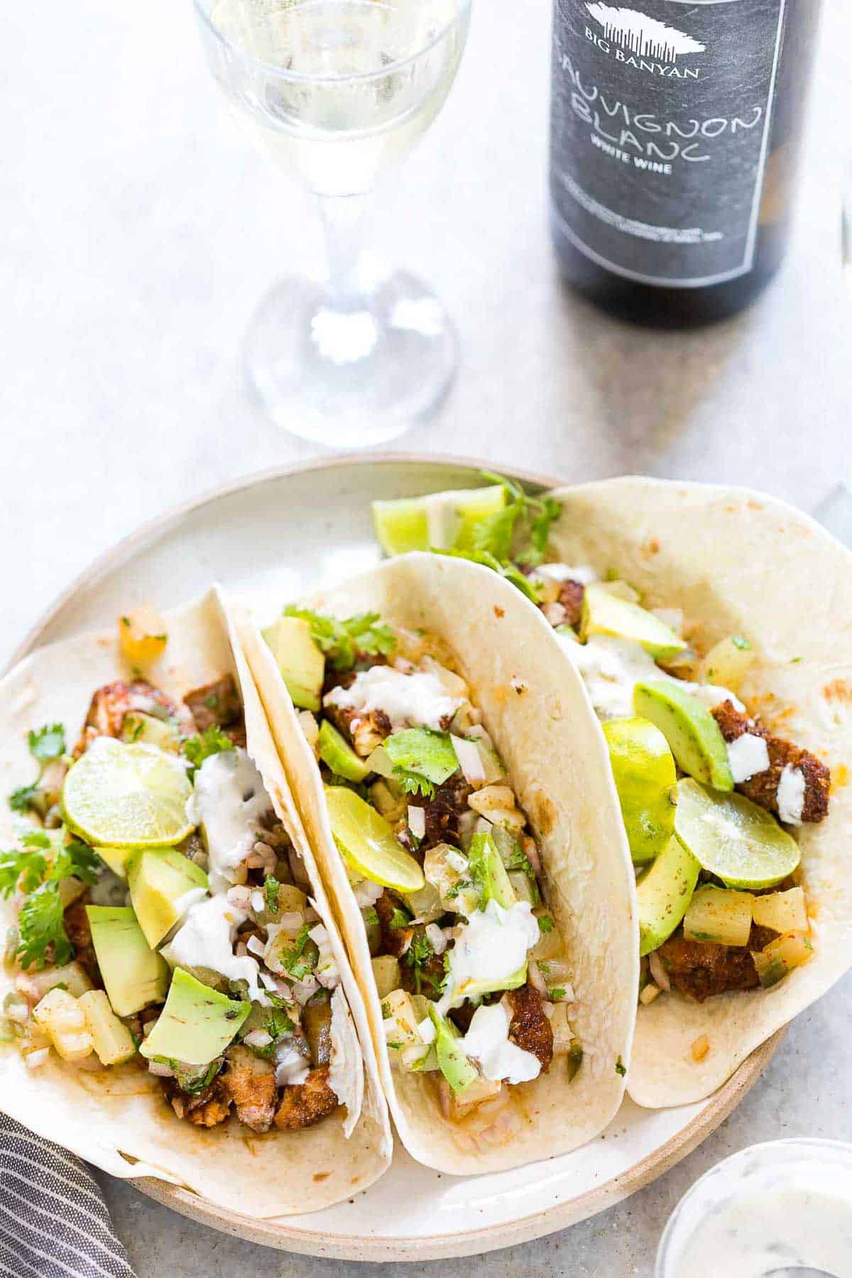 Tilapia Fish Tacos with Pineapple Salsa served on a white plate with a side of Big Banyan's sauvignon blanc.