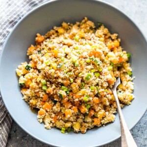 Low Carb Asian Cauliflower Rice topped with sesame seeds, chopped green onions and served in a bowl.