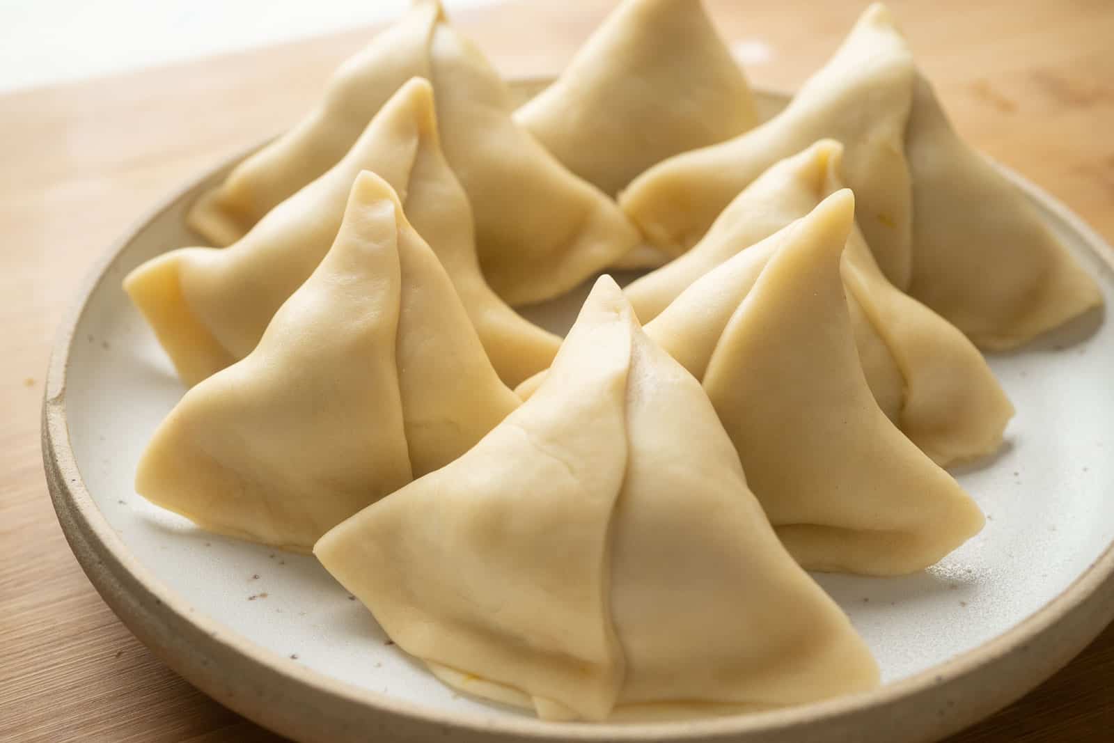Samosas ready to be deep fried kept on a plate