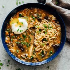A bowl of chinese hot and sour soup with ramen served with a soft boiled egg and green onions ready to eat!