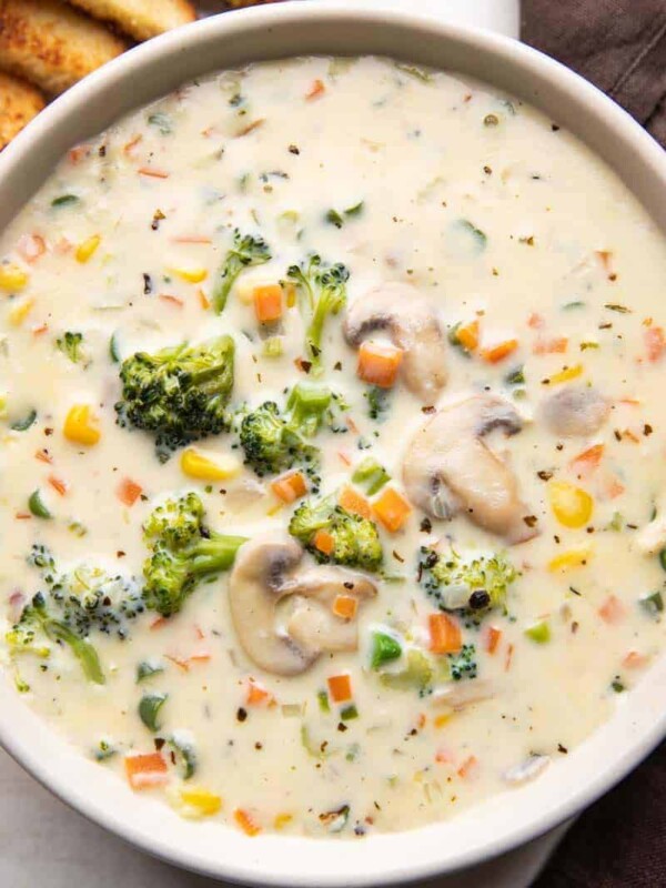 Creamy vegetable soup served in a bowl with bread on the side