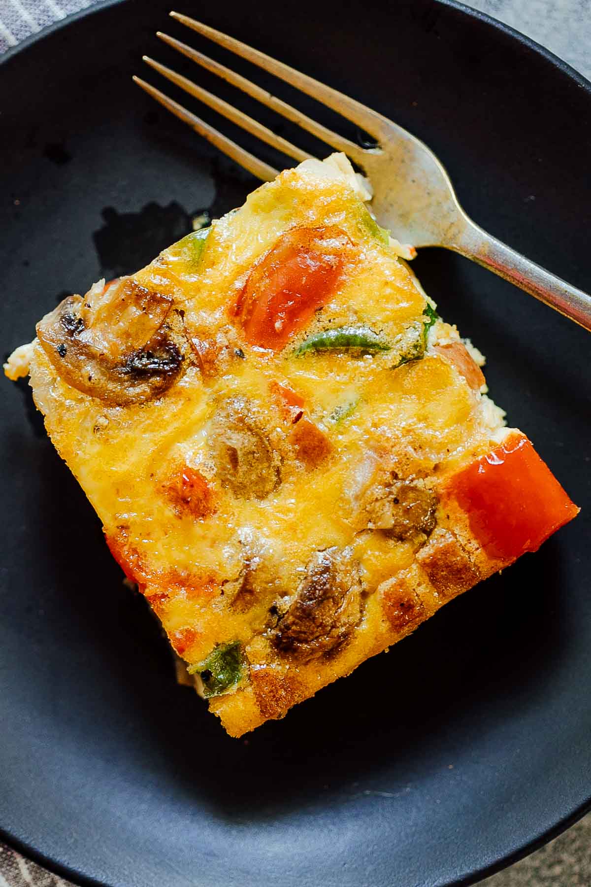 A slice of baked denver omelet breakfast casserole on a plate