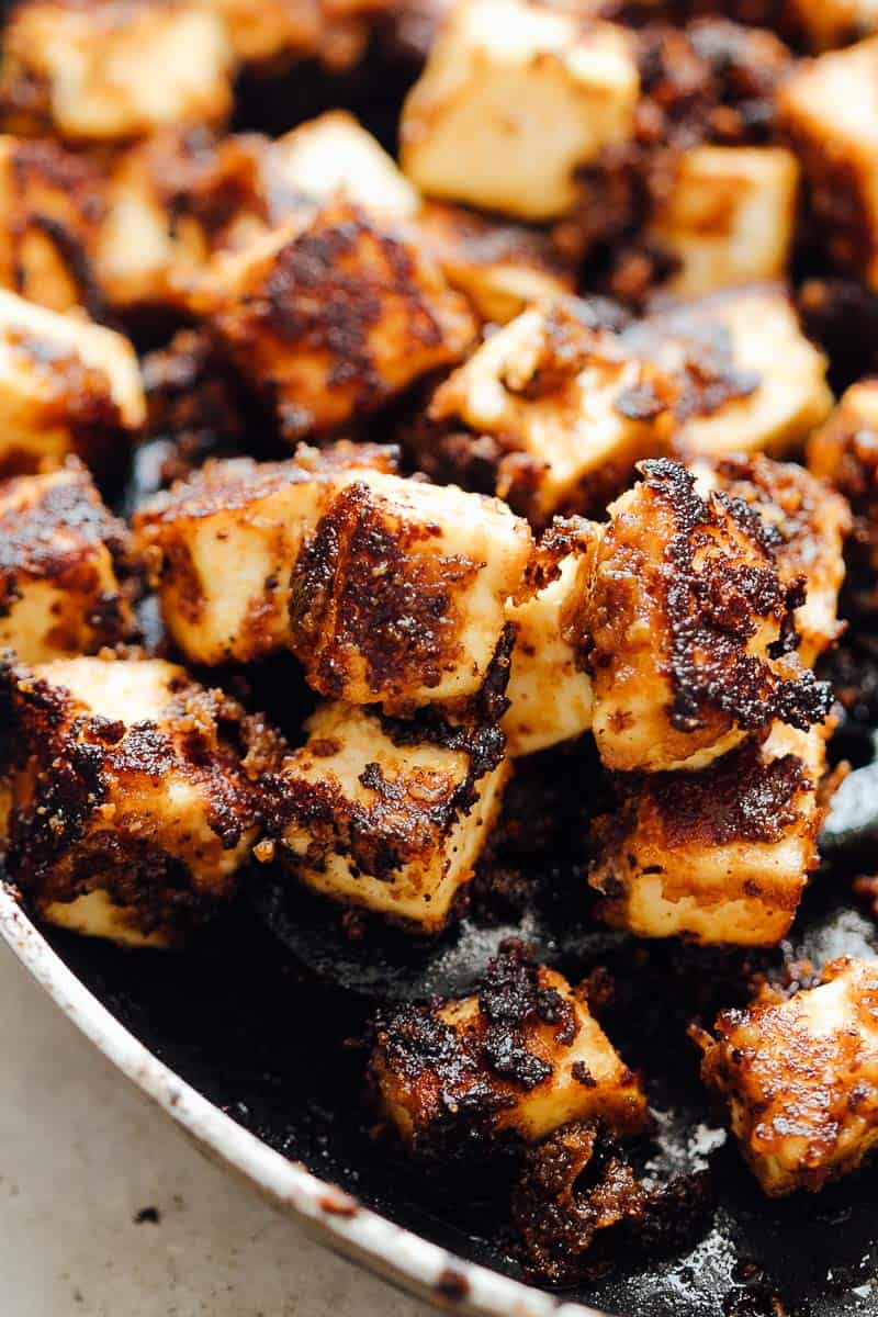 crispy sesame tofu in a pan with crispy bits of caramelised sauce