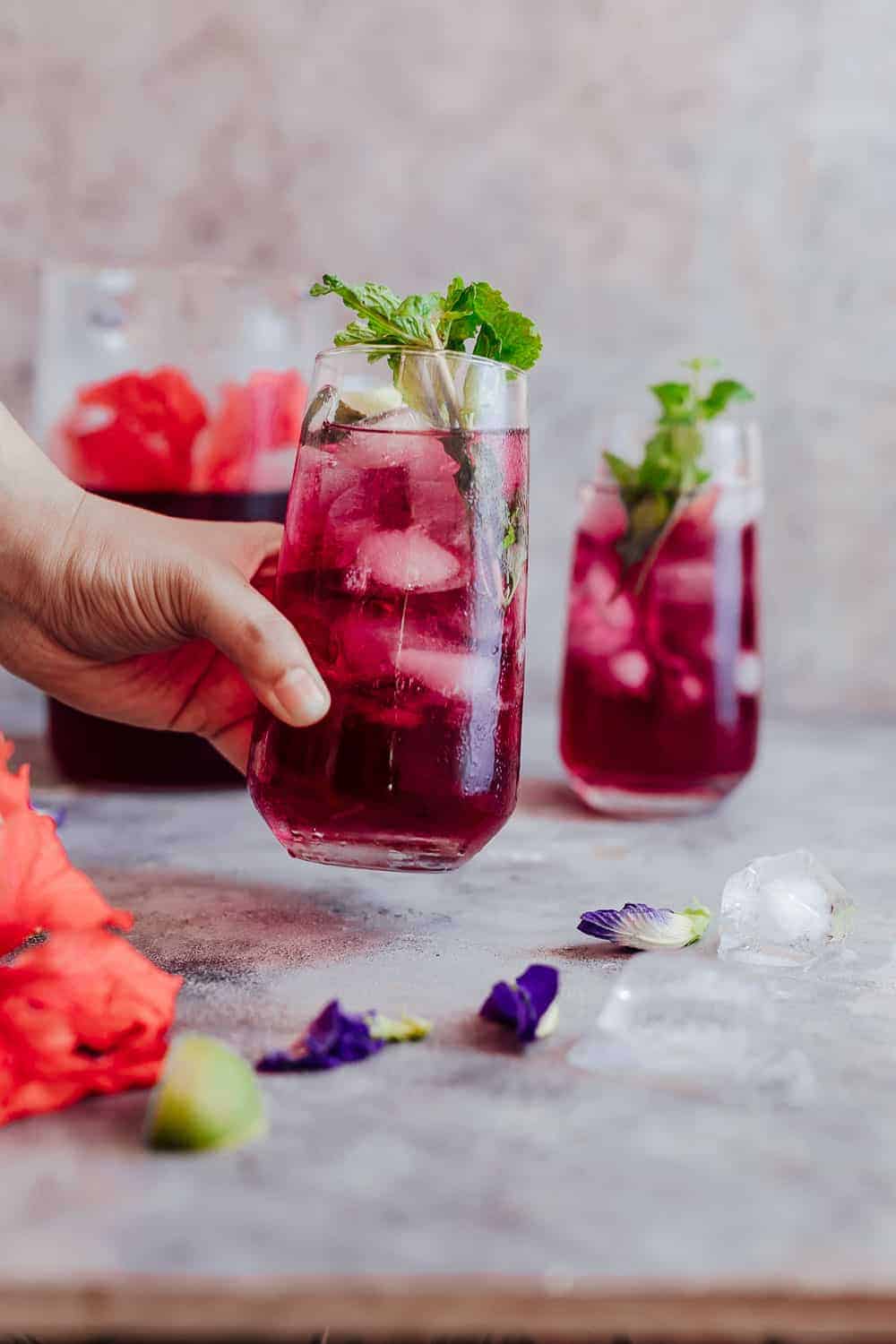 Picking up a glass of chilled hibiscus tea which is served with mint leaves and lemon