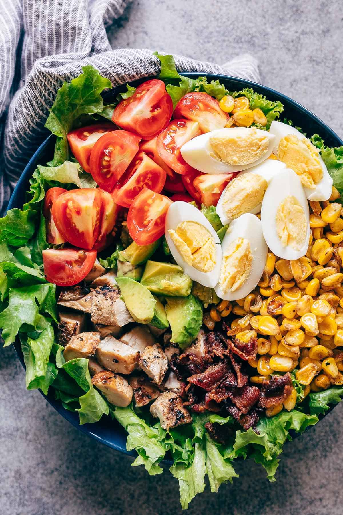 Chicken Cobb Salad served in a bowl - it has lettuce, tomatoes, chicken, bacon, corn and boiled eggs