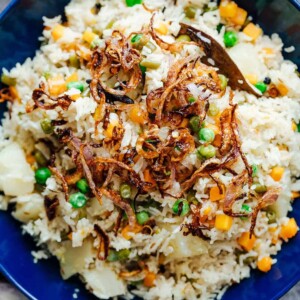 Pressure cooker veg pulao served in a bowl with crispy onions on top