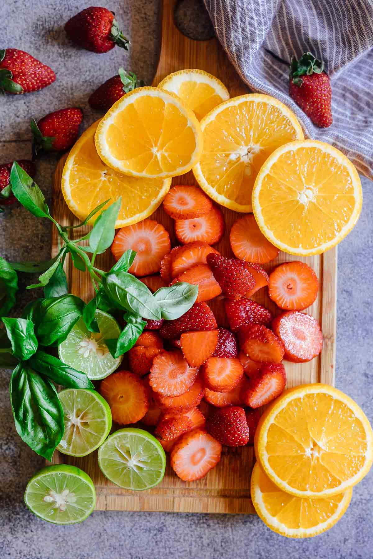 Strawberry Orange White Wine Sangria is a refreshing cocktail that combines the sweetness and flavours of strawberries, oranges, limes and basil with white wine for a fresh take on a traditional sangria. It's the perfect brunch drink that can be made ahead for a crowd. #whitesangria #redwine #cocktails #recipe #drink #summer Cut fruits for strawberry orange white wine sangria