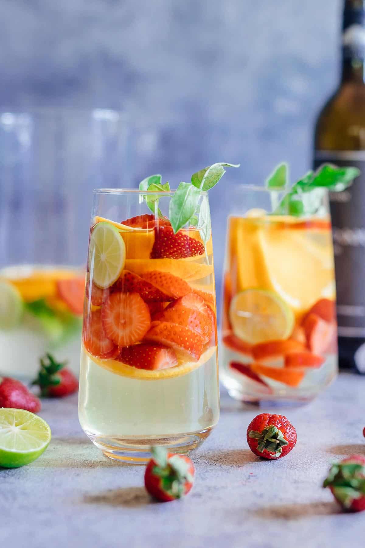Strawberry Orange White Wine Sangria served in two glasses with limes and basil