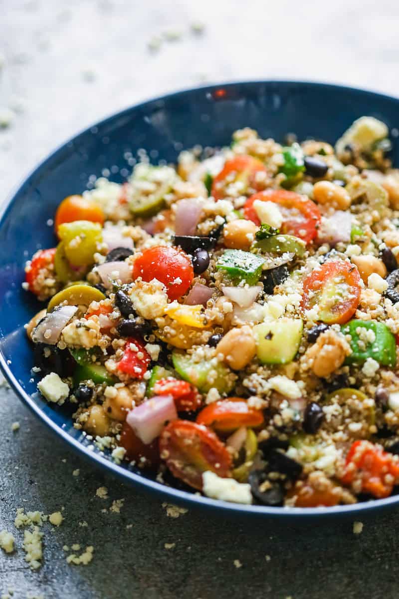 A different angle of mediterranean quinoa salad in a blue bowl sprinkled with feta cheese