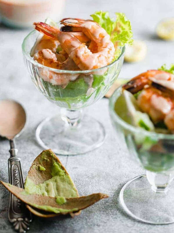 Retro prawn cocktail served in stem glasses with marie rose sauce drizzled over them.