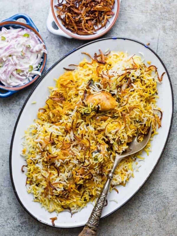 Chicken Biryani served on a platter with crispy fried onions and onion raita.
