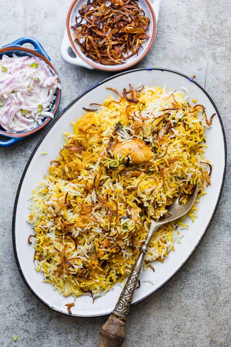 Chicken Biryani served on a platter with crispy fried onions and onion raita
